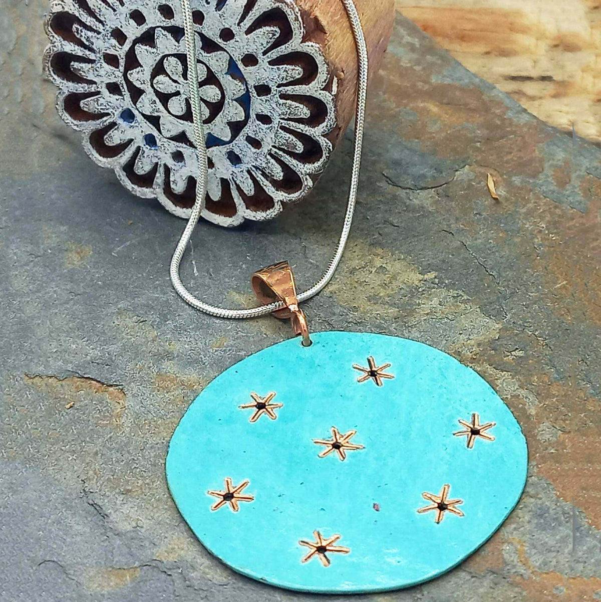 Turquoise pendant with star designs on a stone surface