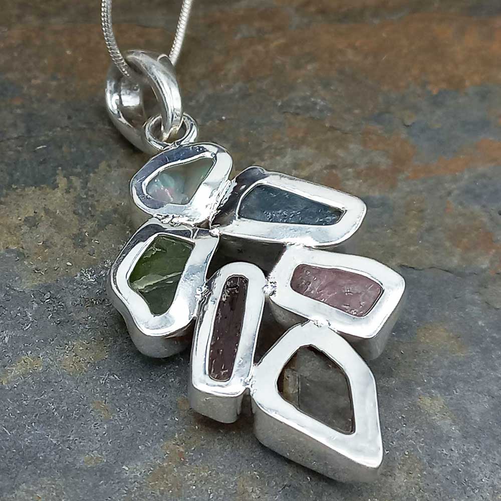 Back of silver pendant with embedded stones on a stone surface