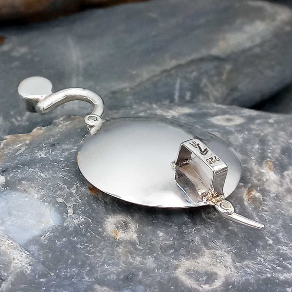 Back of silver pendant on a stone surface