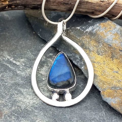 Silver pendant with a blue Labradorite  stone on a stone surface