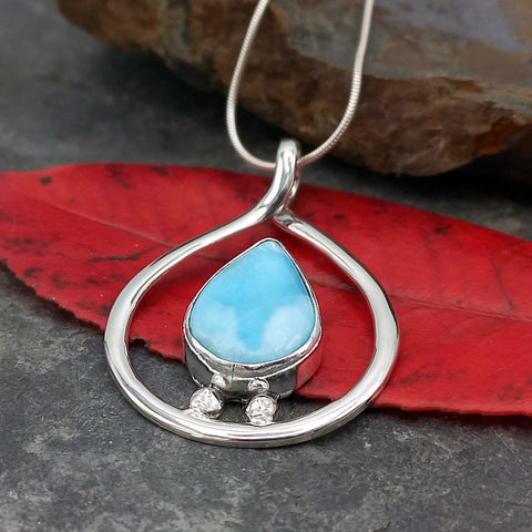 Silver pendant with a blue teardrop-shaped Larimar gemstone on a red leaf