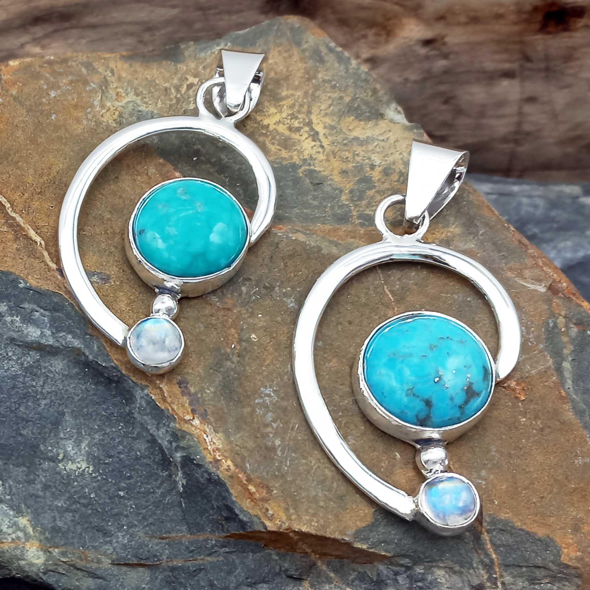 Silver pendants with turquoise stones & moonstone on a stone surface