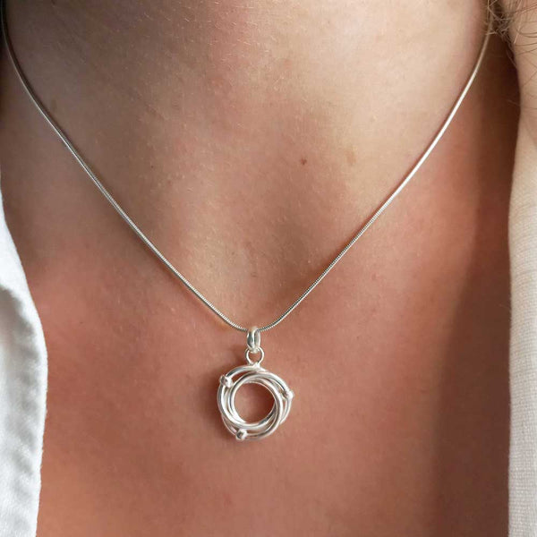 Silver necklace with a circular pendant on a person's neck