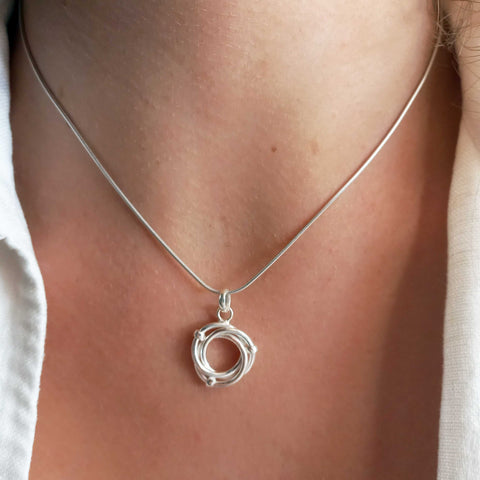 Silver necklace with a circular pendant on a person's neck