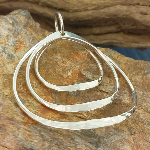 Handmade silver circular pendant on a stone background