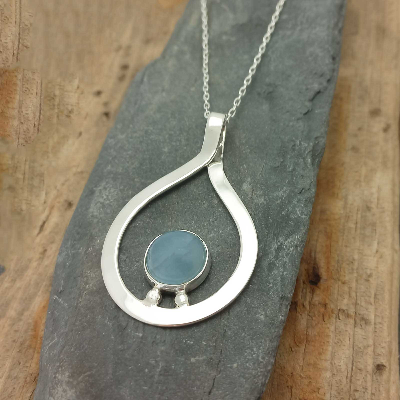 Silver pendant with a blue Aquamarine stone on a stone surface
