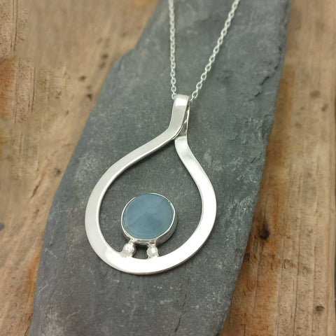 Silver pendant with a blue Aquamarine stone on a stone surface