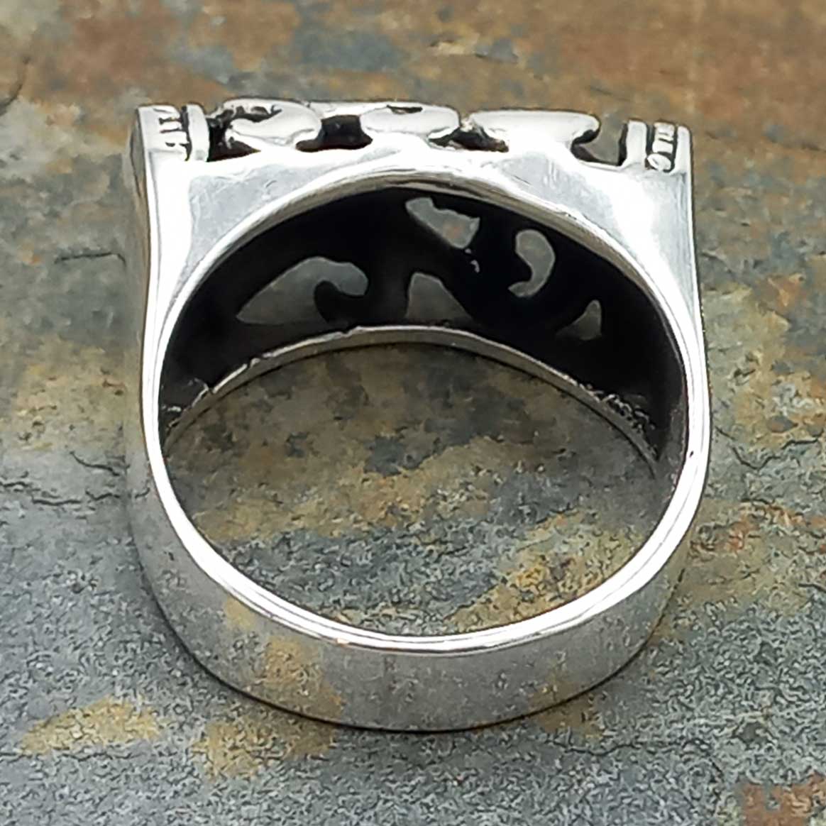 Back of silver ring with intricate design on a textured surface