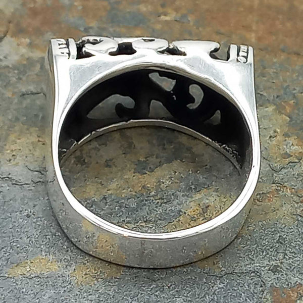Back of silver ring with intricate design on a textured surface
