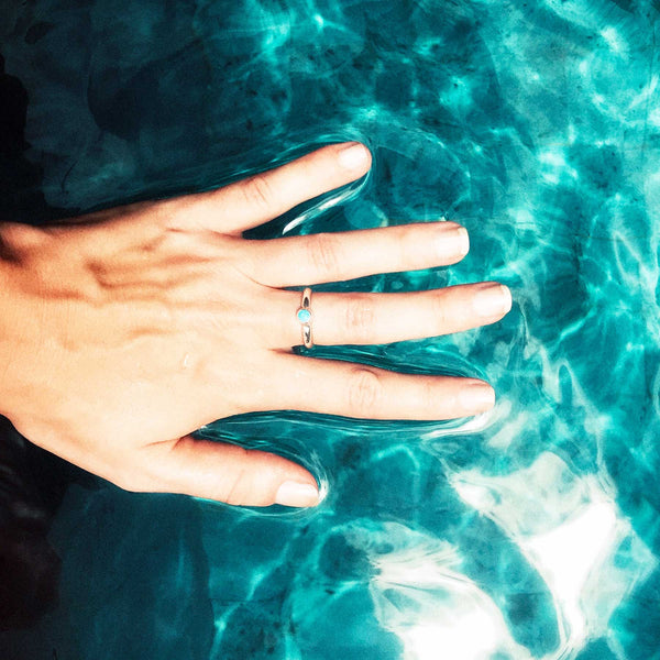 Hand with a ring on a blue water surface