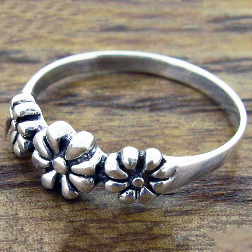 Silver ring with floral designs on a wooden surface