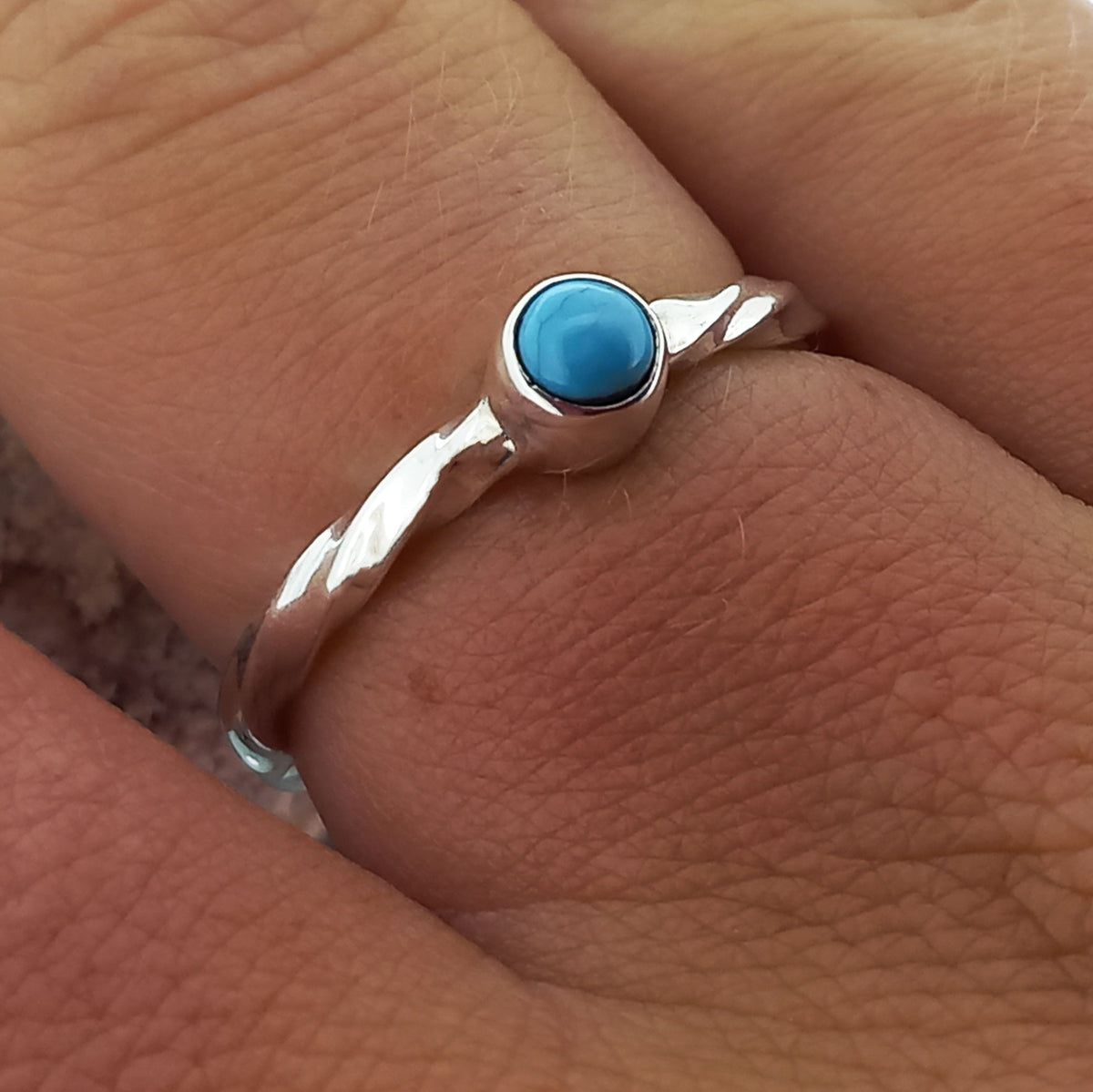 Silver ring with a turquoise stone on a finger
