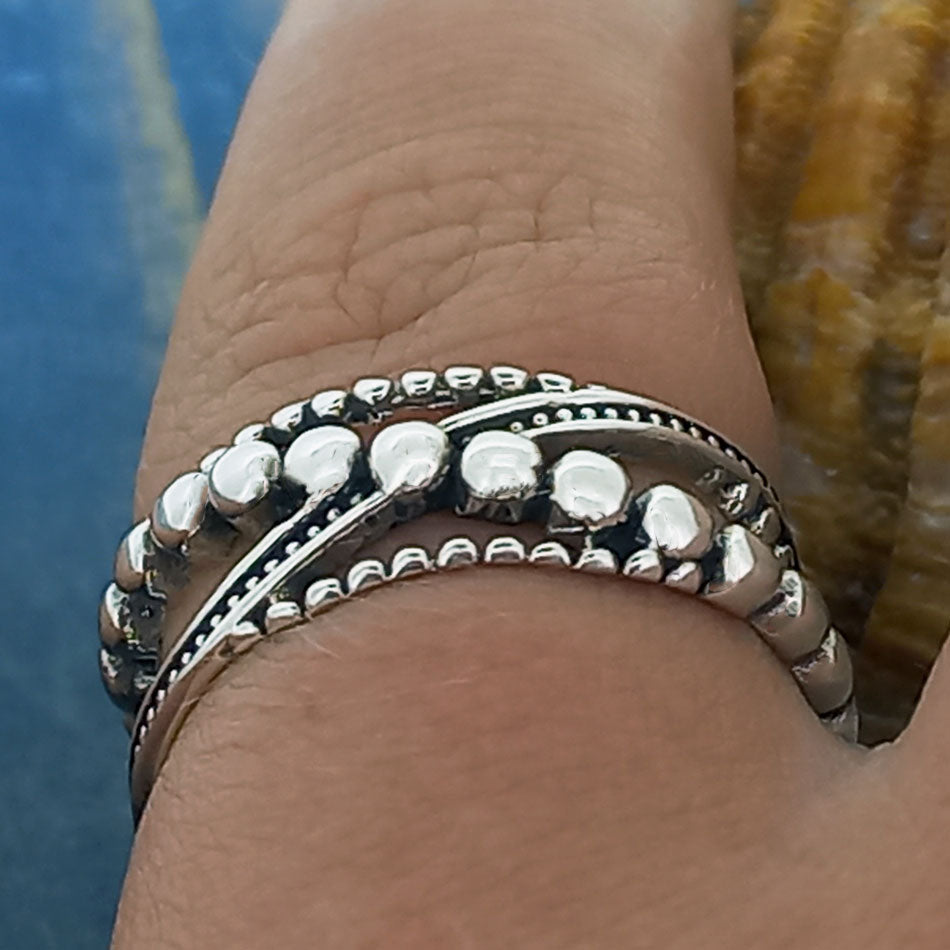 Silver ring with bead design on a person's finger