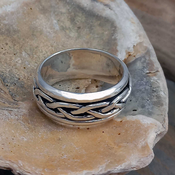 Silver braided ring on a textured stone surface