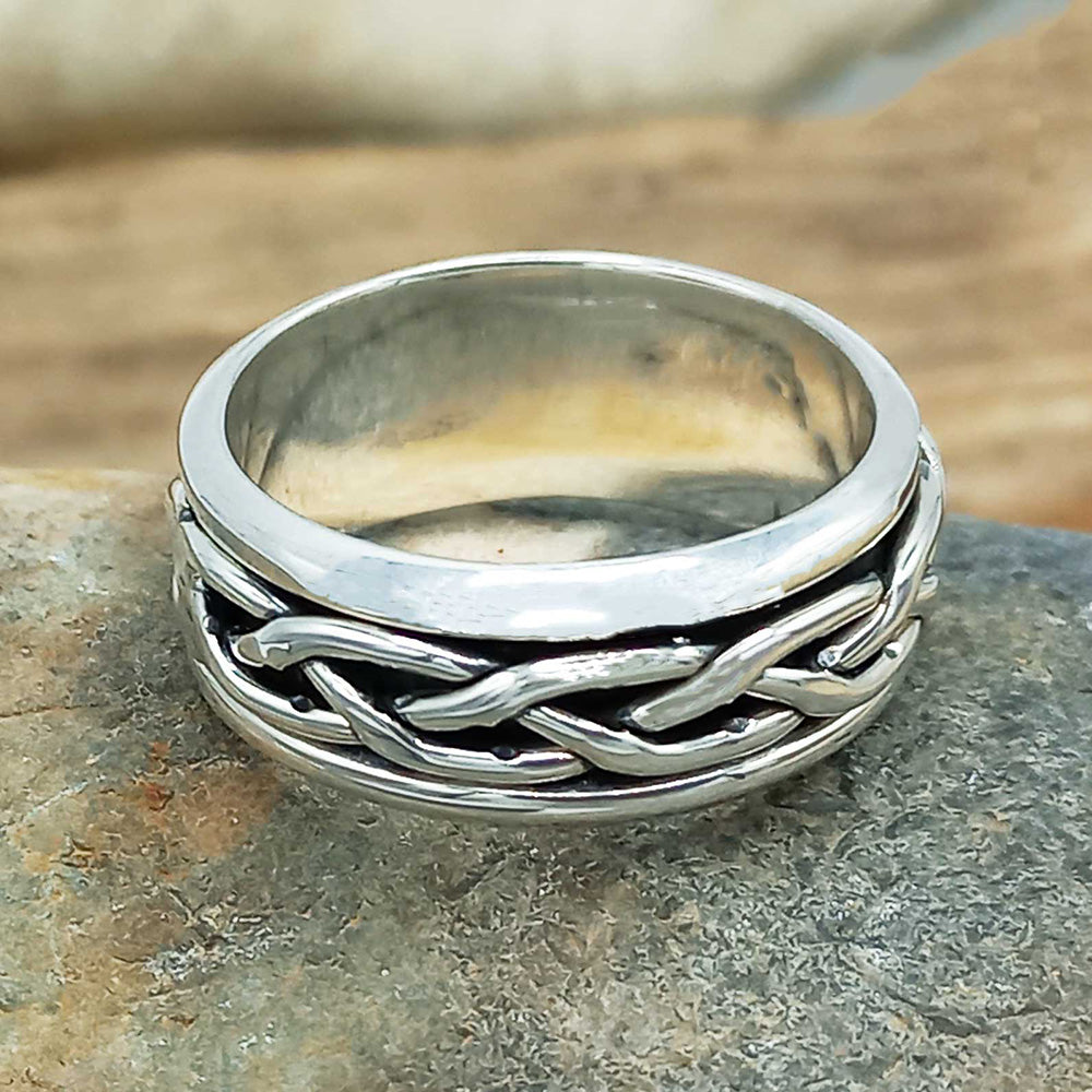 Silver woven ring on a stone surface