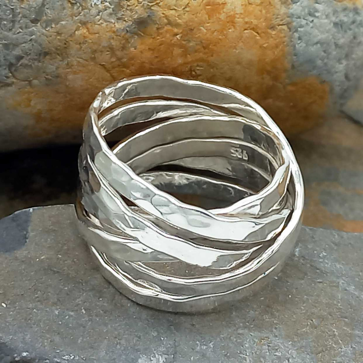 Silver ring with wavy design on a stone surface