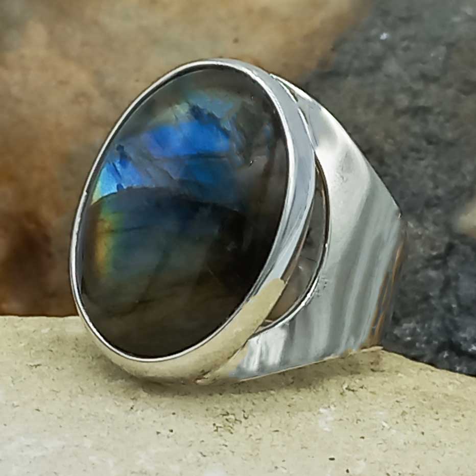 Silver ring with a labradorite stone on a natural stone background