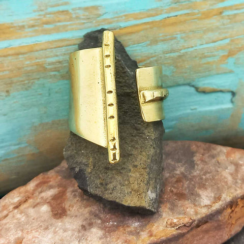 Gold coloured bras ring on a textured stone surface with a wooden background