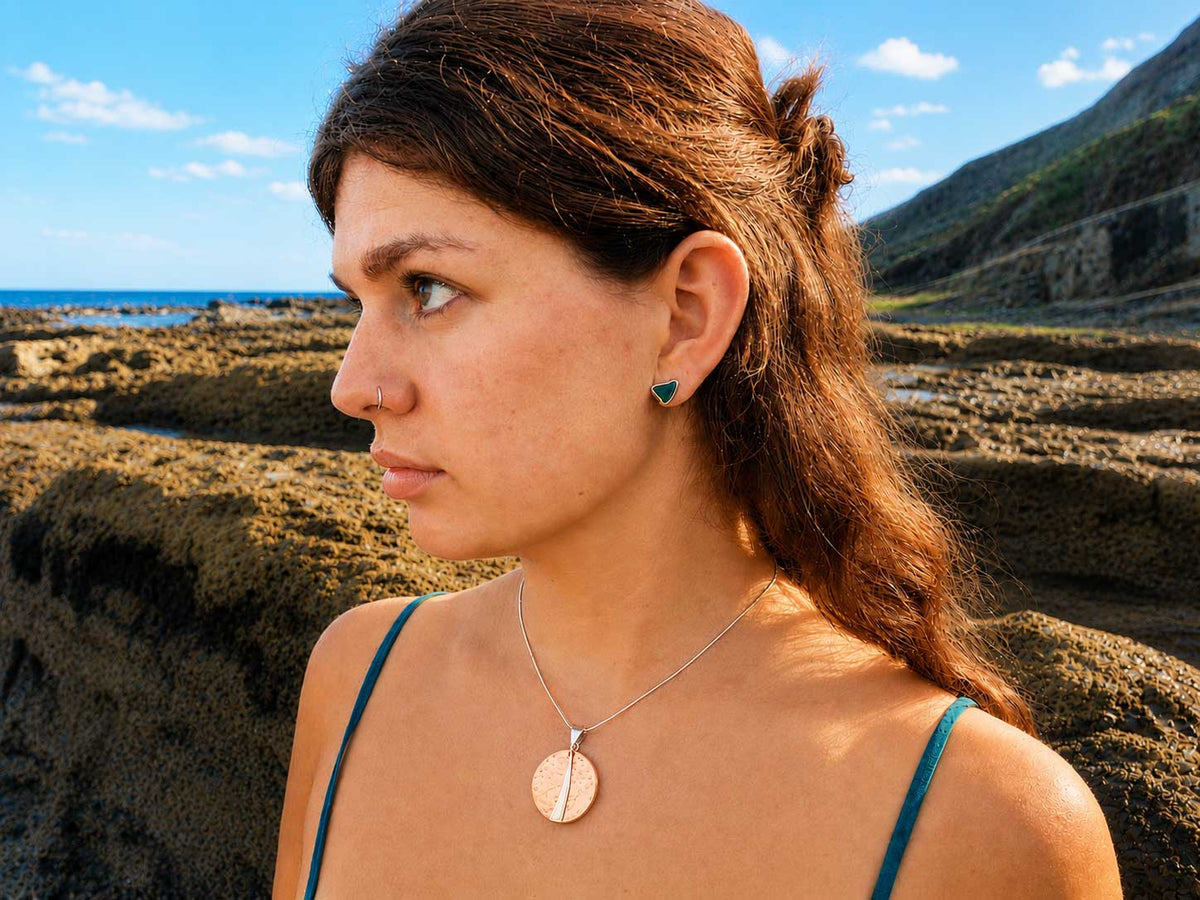 Woman wearing copper disc pendant with sterling silver detail and clasp on a beach