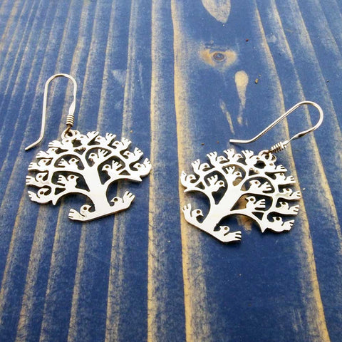 Silver tree-shaped earrings on a blue wooden background