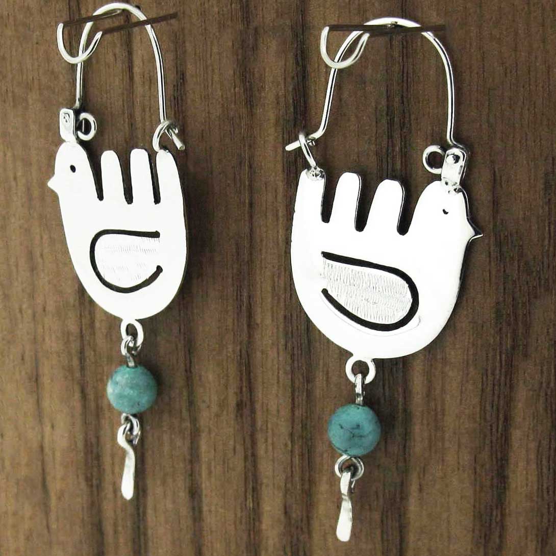 Pair of silver bird-shaped earrings with turquoise beads on a wooden background