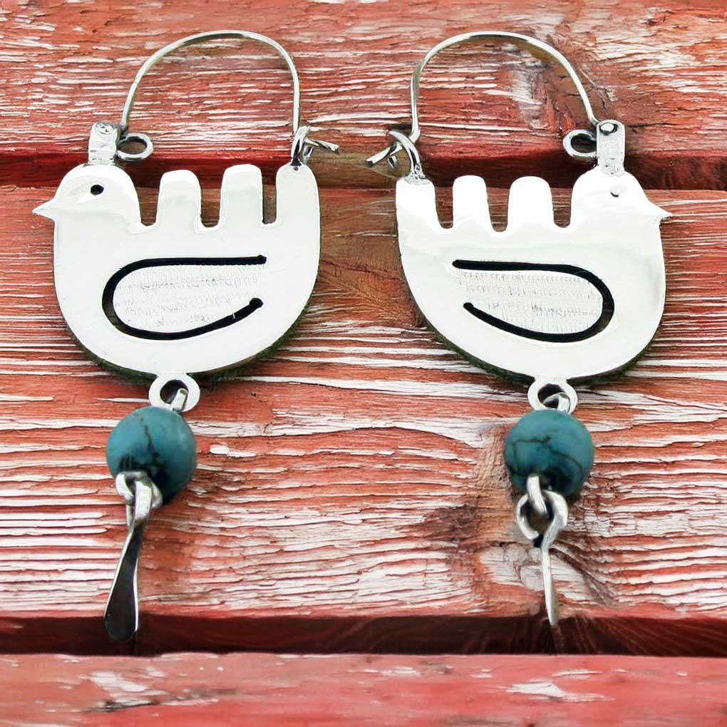 Silver bird-shaped earrings with turquoise beads on a wooden surface