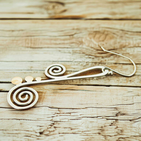 Silver copper spiral earring on a wooden surface