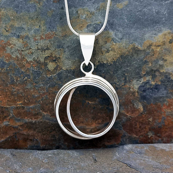 Silver circular pendant necklace on a stone background